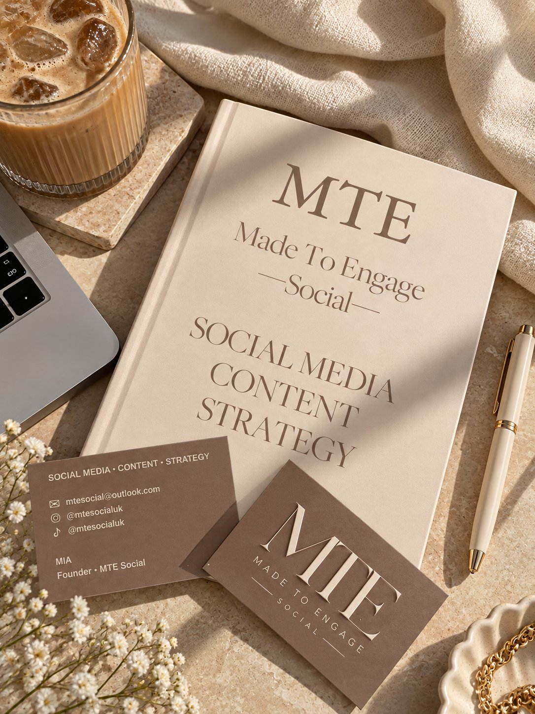 Warm MTE-branded editorial desk with notebook, coffee and creative stationery